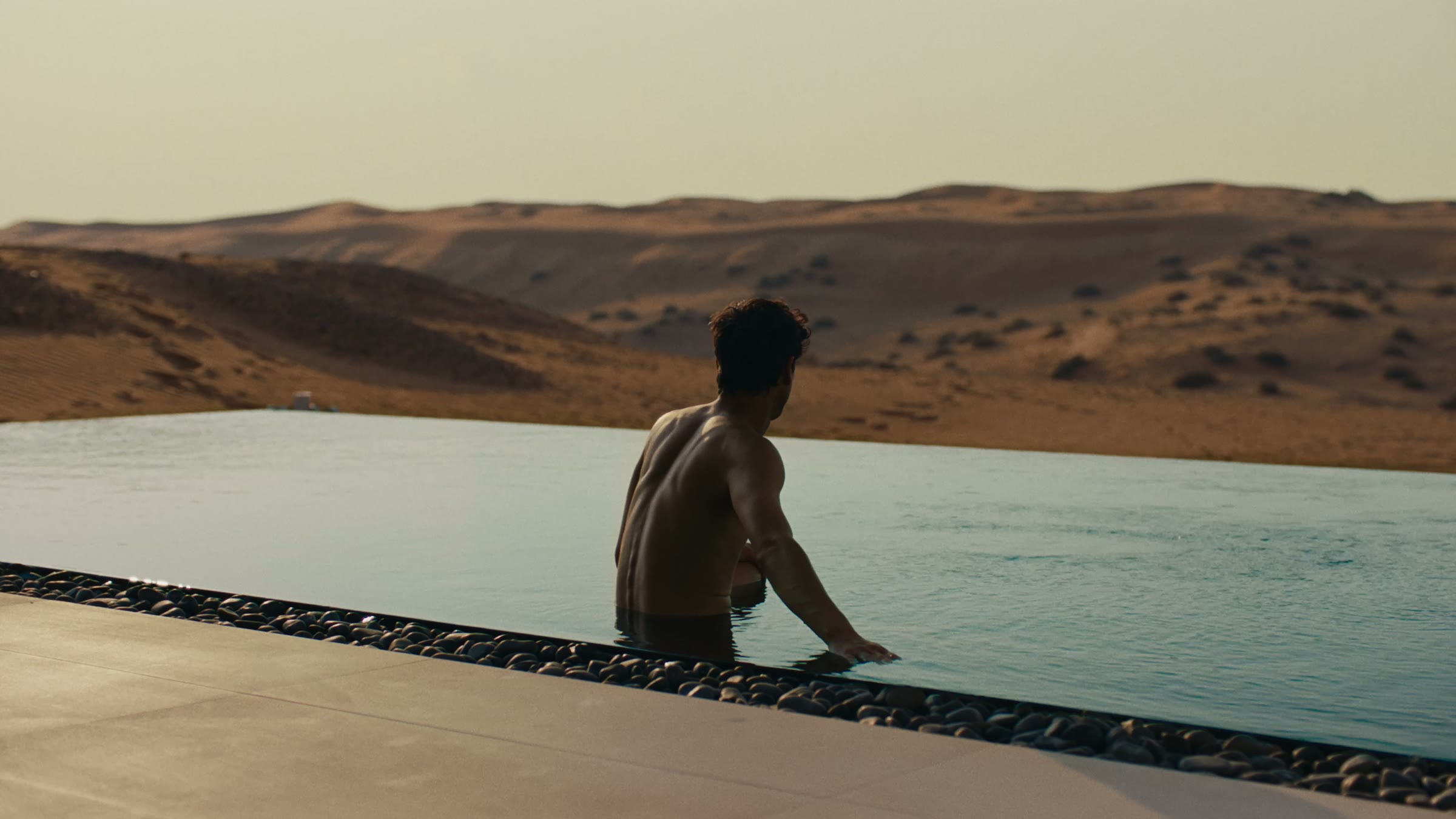 A resident at the edge of an infinity pool above the dunes