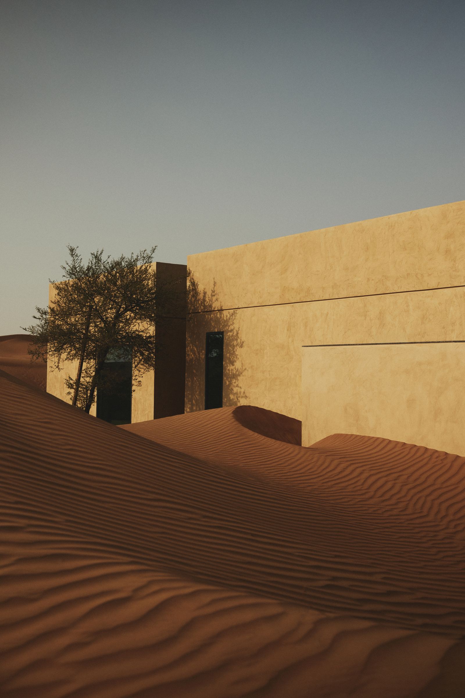 A villa rising from the dunes under a clear sky